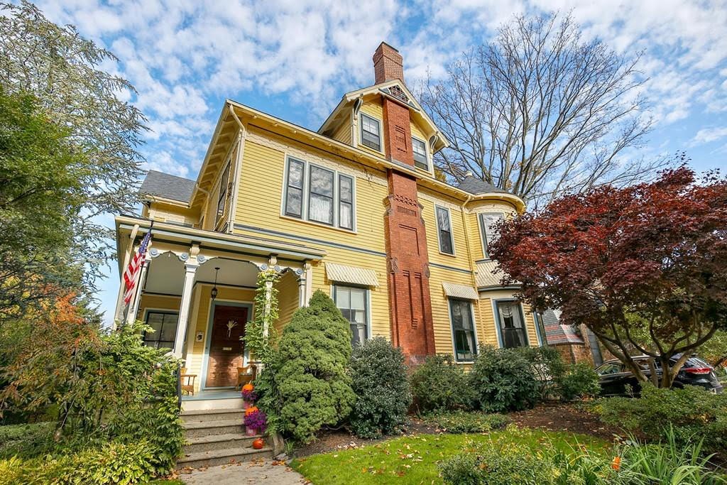 Yellow Victorian home with mature landscaping